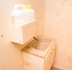 Kleine minimalistische Spüle oder Waschbecken mit Wasserkanister und Schlauch