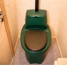 Komposttoilette in Grün und Schwarz im Badbereich mit abschließbarer Tür
